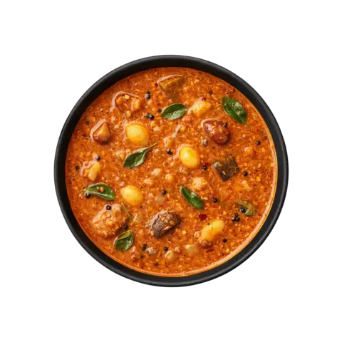 A professional 90-degree top-down flat lay of Pot and Ladle brand ready-to-eat Chettinad Kara Kuzhambu. The deep mahogany-colored tamarind gravy is rich and spicy, featuring whole pearl onions (shallots), garlic cloves, and drumsticks. The surface has a glossy sheen from the traditional gingelly oil tempering with mustard seeds and curry leaves, served in a minimal black bowl on a seamless white background.