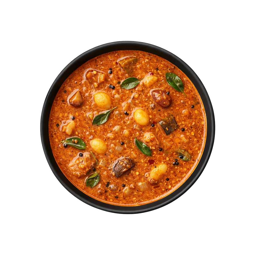 A professional 90-degree top-down flat lay of Pot and Ladle brand ready-to-eat Chettinad Kara Kuzhambu. The deep mahogany-colored tamarind gravy is rich and spicy, featuring whole pearl onions (shallots), garlic cloves, and drumsticks. The surface has a glossy sheen from the traditional gingelly oil tempering with mustard seeds and curry leaves, served in a minimal black bowl on a seamless white background.