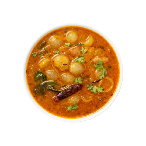 A professional 90-degree top-down flat lay of Pot and Ladle brand ready-to-eat Chinna Vengaya Sambar. The medium-thick, golden-orange lentil gravy features numerous whole, tender, translucent pearl onions (shallots). Garnished with a fresh tempering of mustard seeds, a whole dried red chili, and a sprinkle of fresh coriander, served in a minimal white bowl on a seamless white studio background.