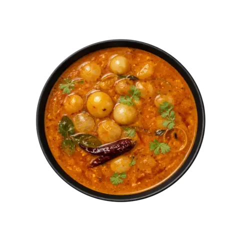 A professional 90-degree top-down flat lay of Pot and Ladle brand ready-to-eat Chinna Vengaya Sambar. The medium-thick, golden-orange lentil gravy features numerous whole, tender, translucent pearl onions (shallots). Garnished with a fresh tempering of mustard seeds, a whole dried red chili, and a sprinkle of fresh coriander, served in a minimal black bowl on a seamless white studio background.