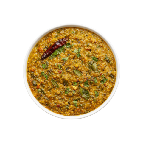 A professional 90-degree flat lay of Pot and Ladle brand ready-to-eat Gongura Pappu. The dish features creamy yellow lentils slow-cooked with tangy, finely chopped green roselle leaves (gongura) and finished with a tempering of golden garlic cloves, mustard seeds, and dried red chilies. Centered in a plain white bowl on a seamless, pure white studio background.