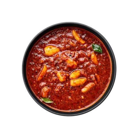 A professional 90-degree top-down flat lay of Pot and Ladle brand ready-to-eat Poondu Kuzhambu. The dish features a dark, concentrated tamarind-based gravy loaded with numerous whole, slow-cooked golden garlic cloves. The glossy, spice-flecked surface is tempered with mustard seeds and fresh curry leaves, presented in a minimal black bowl on a seamless white studio background.