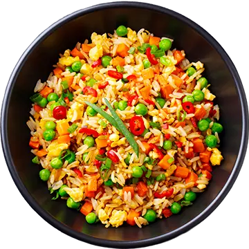 Top view of ready-to-eat Indian fried rice with egg and mixed vegetables served on a dark stone background.